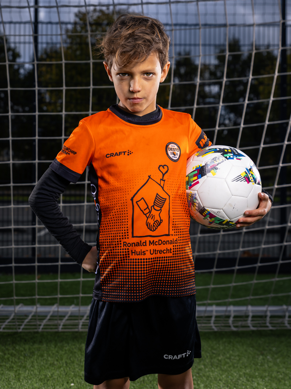 Energiek en Dynamisch PhiPho Voetbal Portret Davy C.O.V. Desto met off-camera flash. Davy draagt het knaloranje en zwarte clubtenue, van sportmerk Craft en DAKA, sponsor Ronald McDonald Huis Utrecht. Davy kijkt met een verbeten blik in de camera.